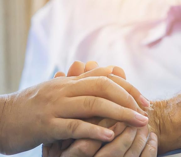 Older man and younger woman holding hands in bed